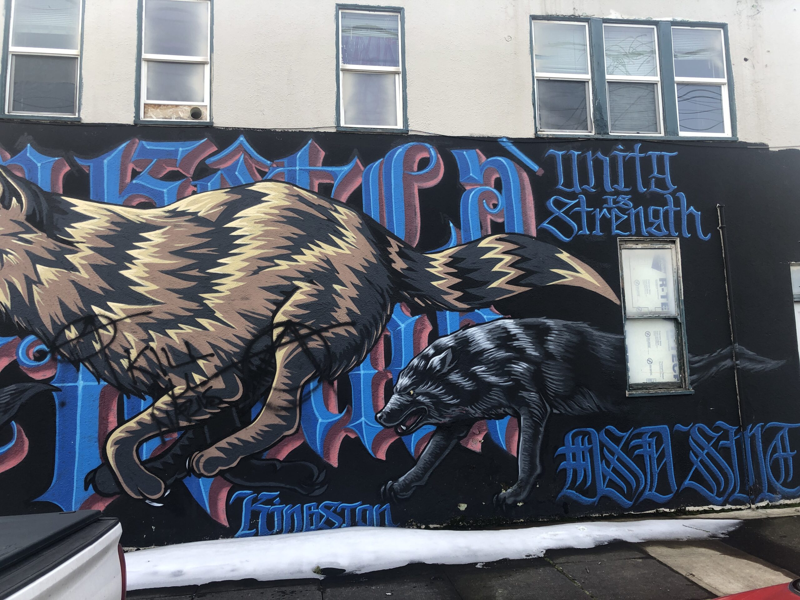 Mural painted on side of wall with fierce looking wolves, Germanic lettering, some reading: Unity Is Strength